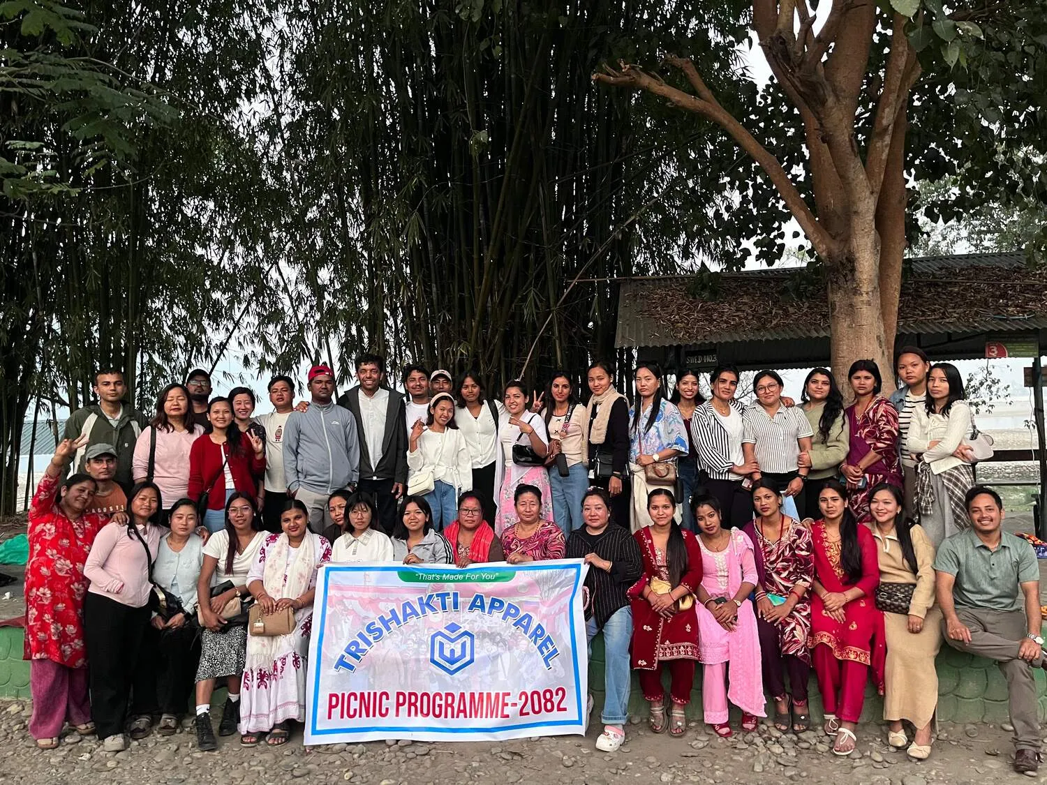 The Trishakti Apparel workforce at the 2082 company picnic holding the company banner